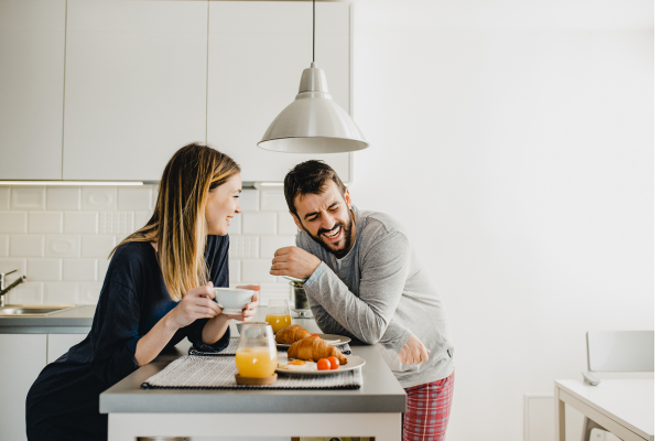 Couple laughing over breakfast in modern white kitchen