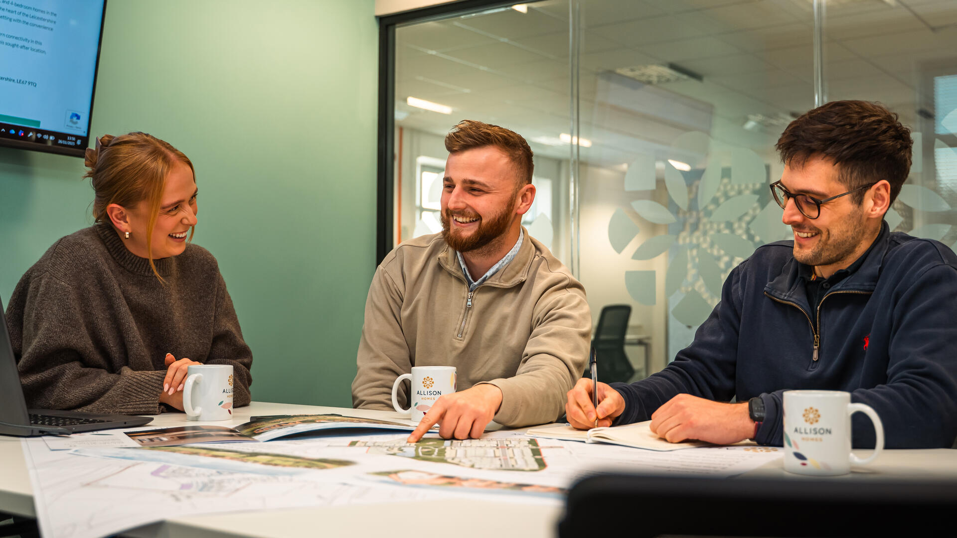 Colleagues laugh and smile during a meeting in the office