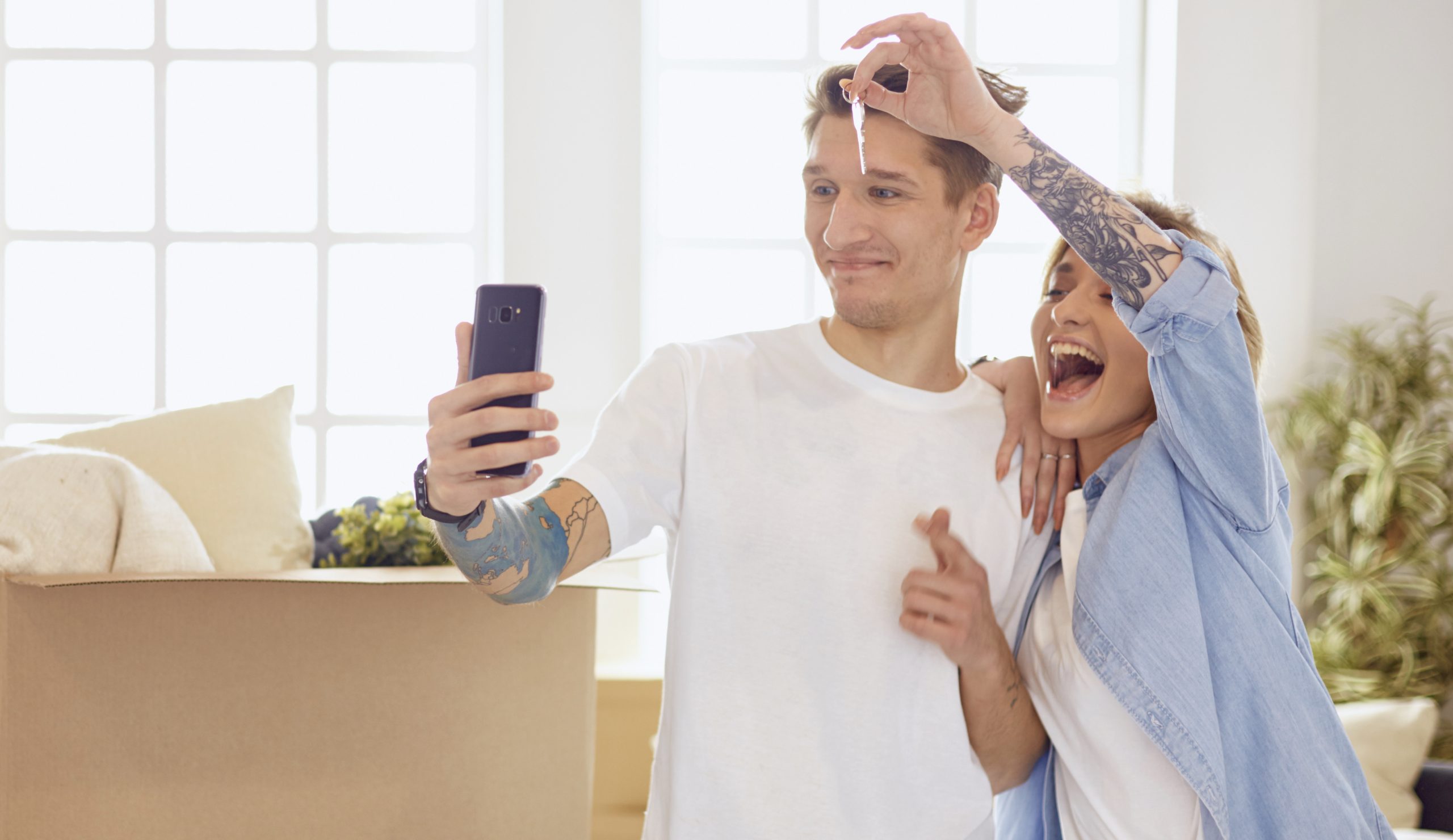 Happy smiling young couple showing a pair of keys of their new house.